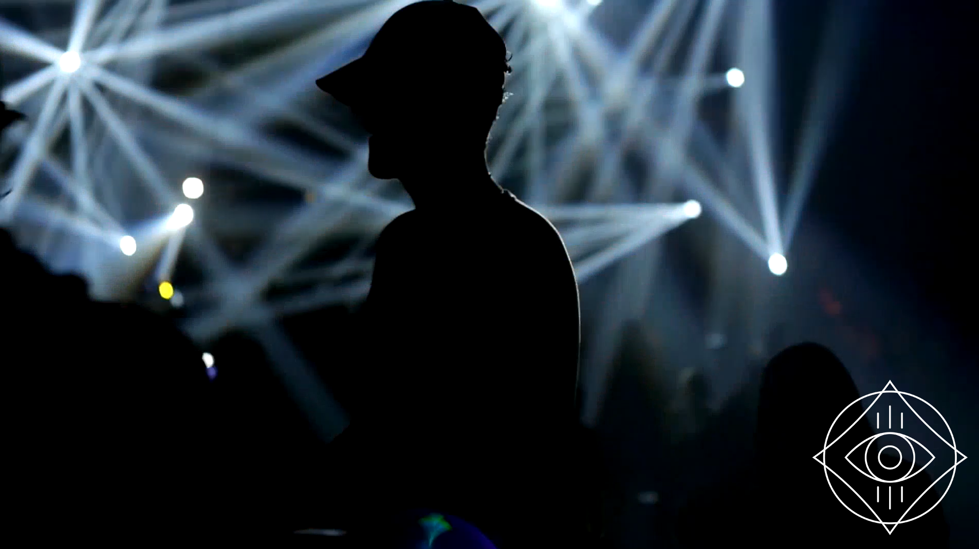 A silhouette of a guy at a concert wearing a hat